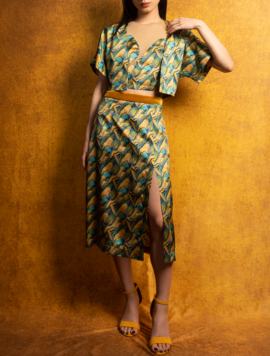 A woman wears a silk crop top, skirt, and jacket. The set features the PANORAMA Print and is inspired by Chinese landscape paintings. She exudes grace in this Modern Chinese chic style.