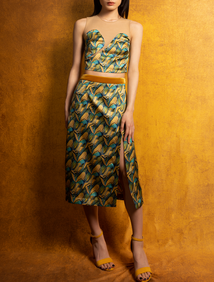 A woman wears a silk crop top, skirt, and jacket. The set features the PANORAMA Print and is inspired by Chinese landscape paintings. She exudes grace in this Modern Chinese chic style.