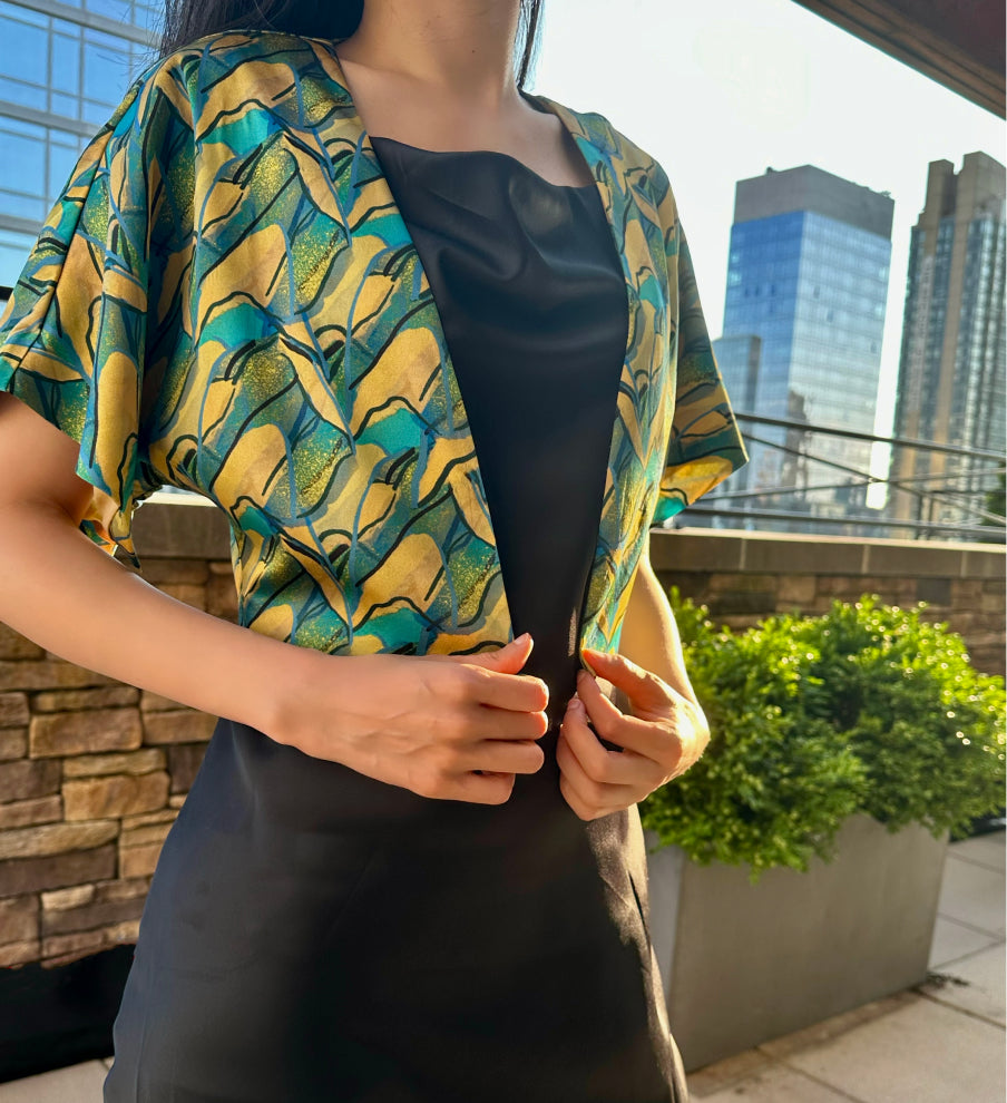 A woman wears the silk PANORAMA jacket over a black slip dress. She exudes grace in this Modern Chinese chic style.