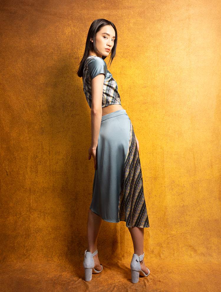 A model wears a silk crop top and high-waisted skirt featuring the BRONZE MOUNTAIN Print. She exudes grace in this Modern Chinese chic style. 