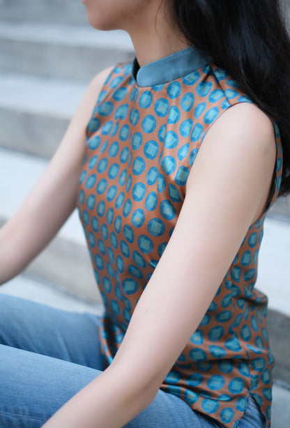 A women wears a silk sleeveless top featuring a custom print and Mandarin collar, exuding grace in a Modern Chinese chic style.